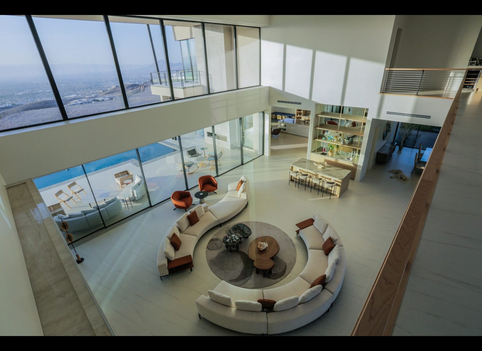 Double height great room with curved sofas and valley views