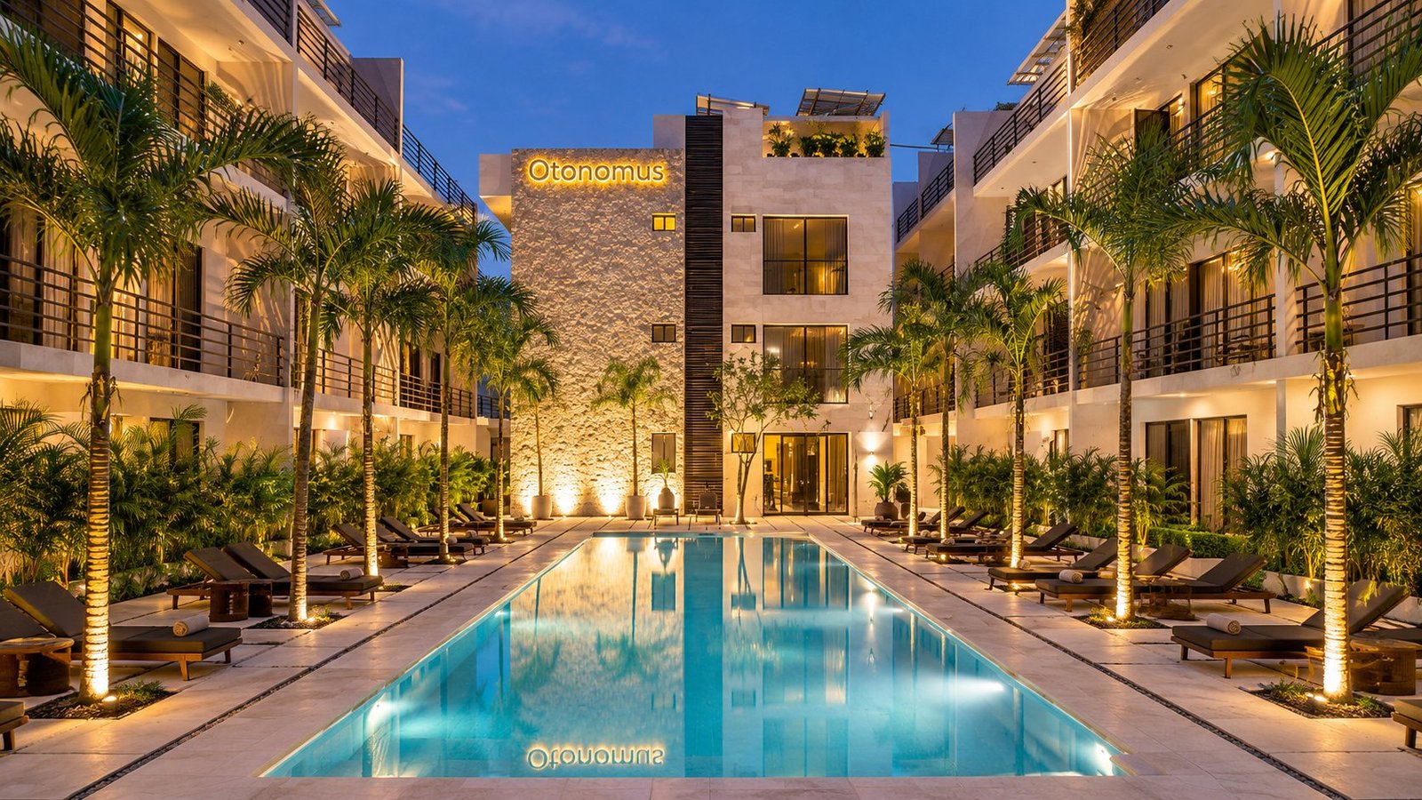 Otonomus Tulum courtyard pool lined with palms at dusk